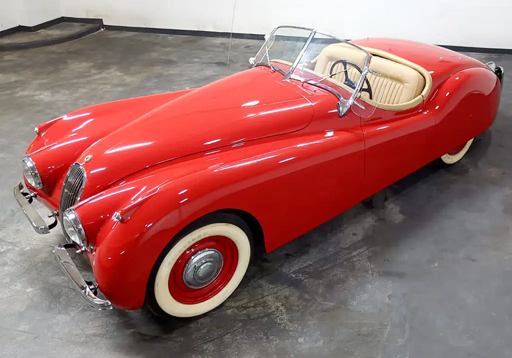 Front view of a restored 1954 Jaguar XK120 with a sleek red paint job