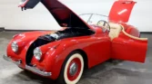 Front view of a restored 1954 Jaguar XK120 with a sleek red paint job