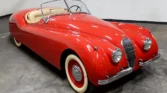 Front view of a restored 1954 Jaguar XK120 with a sleek red paint job