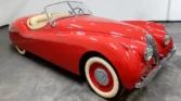 Front view of a restored 1954 Jaguar XK120 with a sleek red paint job