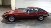 Side view of a 1970 Jaguar E-Type 4.2 (2+2) showcasing its sleek coupe design and metallic maroon color Classic Cars for sale