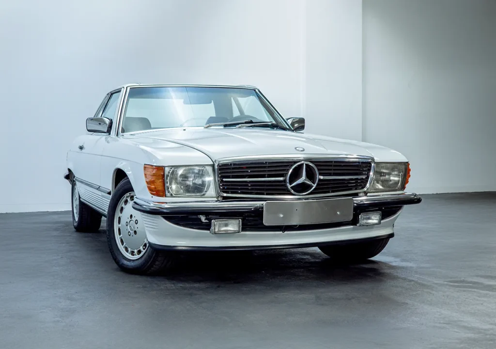 Front view of a 1988 Mercedes Benz 560SL for sale, a classic car with an Arctic White exterior. Auto Mart Motors