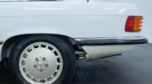 Side view of a 1988 Mercedes Benz 560SL for sale, showcasing its vintage convertible design in Arctic White. Auto Mart Motors